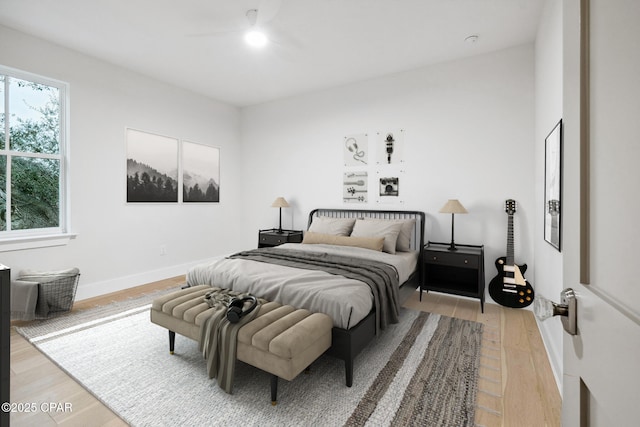 bedroom featuring a ceiling fan, light wood-style flooring, and baseboards