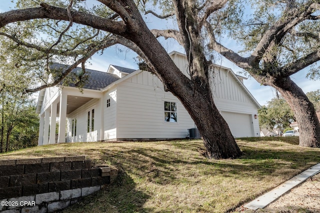 view of side of home with a shingled roof, a lawn, board and batten siding, a garage, and cooling unit