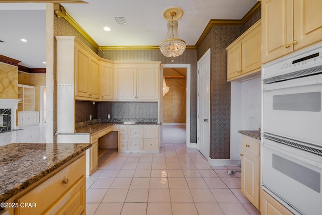 kitchen featuring a fireplace, double oven, decorative light fixtures, dark stone counters, and ornamental molding