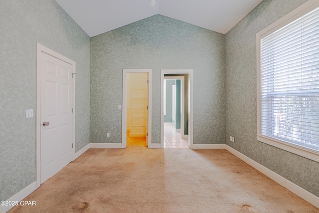 carpeted empty room featuring vaulted ceiling