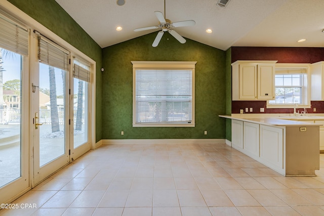 kitchen with sink, ceiling fan, white cabinets, light tile patterned flooring, and vaulted ceiling