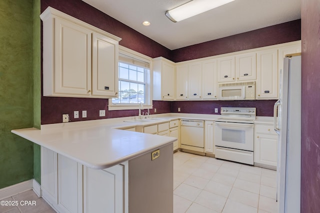 kitchen featuring sink, light tile patterned floors, white appliances, and kitchen peninsula