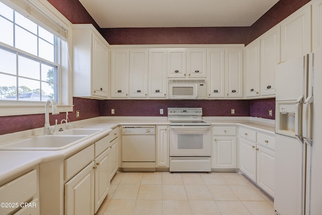 kitchen featuring white cabinetry, sink, white appliances, and light tile patterned floors