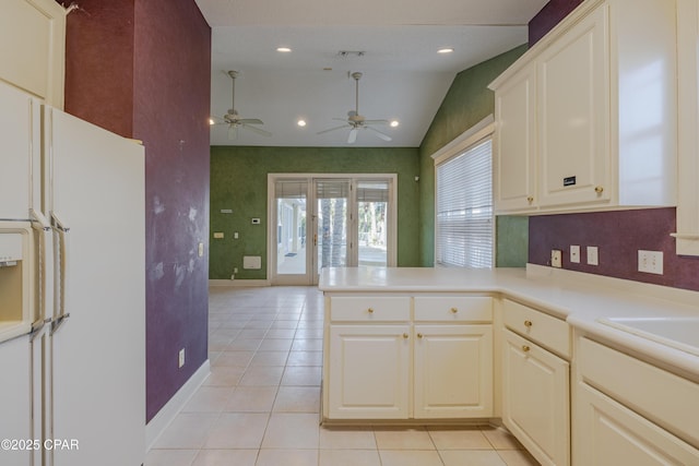 kitchen featuring lofted ceiling, white refrigerator with ice dispenser, light tile patterned floors, ceiling fan, and kitchen peninsula