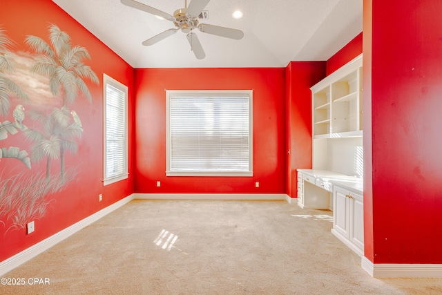 empty room with light carpet, built in desk, and ceiling fan