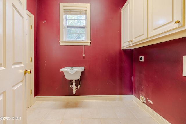 clothes washing area with cabinets, electric dryer hookup, and light tile patterned floors