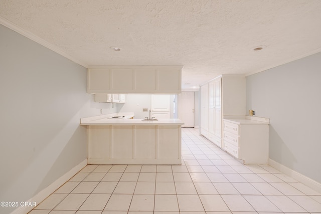 kitchen with light tile patterned floors, sink, crown molding, a textured ceiling, and kitchen peninsula