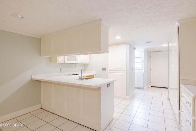 kitchen with sink, ornamental molding, light tile patterned floors, kitchen peninsula, and a textured ceiling