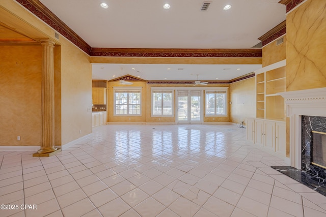 unfurnished living room featuring a wealth of natural light, a fireplace, built in features, and ornate columns