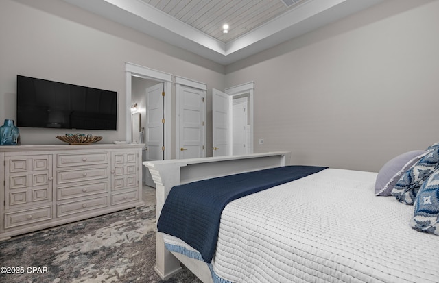 bedroom with carpet flooring, wooden ceiling, and a tray ceiling