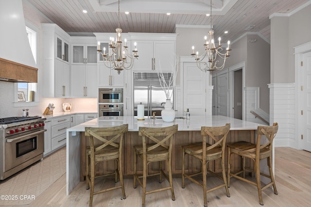 kitchen featuring a large island, an inviting chandelier, high end appliances, white cabinets, and custom exhaust hood