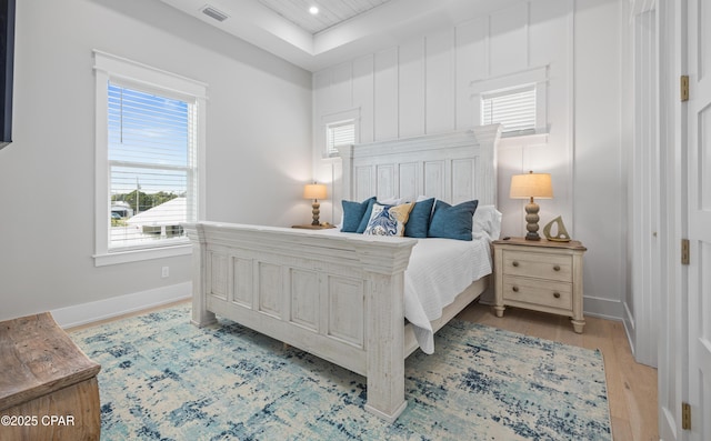 bedroom featuring light hardwood / wood-style flooring and a tray ceiling