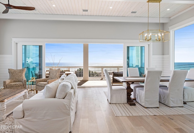 dining space featuring ceiling fan with notable chandelier, light hardwood / wood-style flooring, wooden ceiling, and a water view