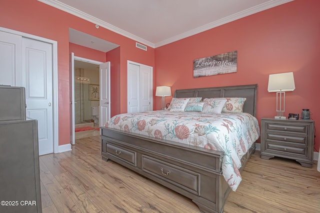 bedroom with ornamental molding, ensuite bathroom, light hardwood / wood-style floors, and two closets