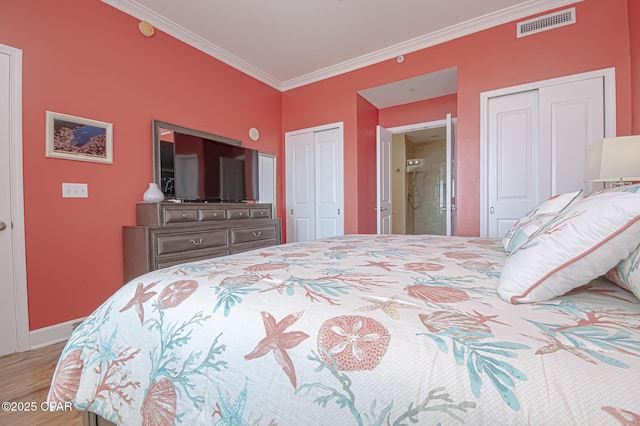 bedroom featuring ornamental molding, light hardwood / wood-style flooring, and two closets