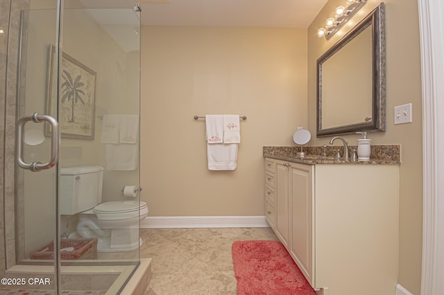 bathroom featuring vanity, a shower with shower door, and toilet