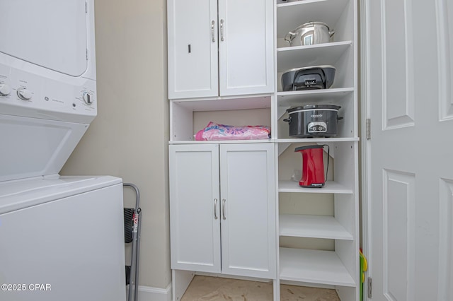 laundry room featuring cabinets and stacked washer and clothes dryer