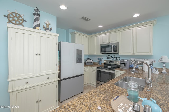 kitchen with appliances with stainless steel finishes, sink, and dark stone counters