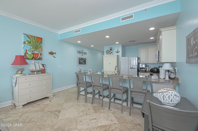 kitchen with a kitchen bar, white cabinetry, white refrigerator, ornamental molding, and kitchen peninsula