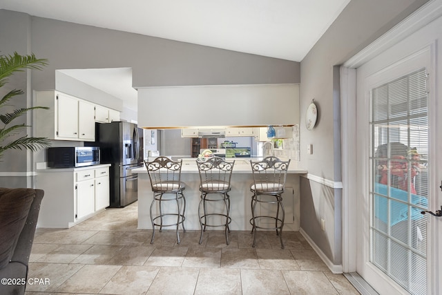 kitchen with white cabinetry, a breakfast bar, appliances with stainless steel finishes, and kitchen peninsula