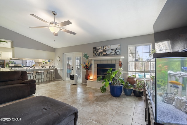 living room with french doors, ceiling fan, a fireplace, and vaulted ceiling