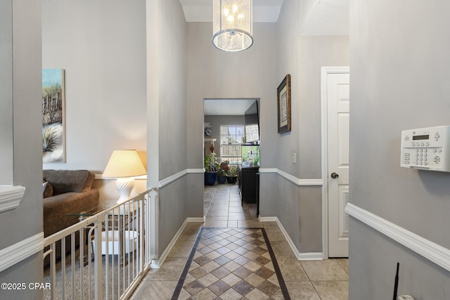 hallway with a chandelier, a high ceiling, and light tile patterned floors