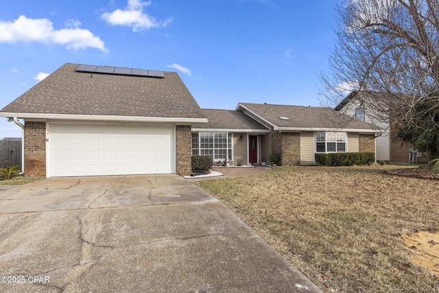 ranch-style house with a garage, a front lawn, and solar panels