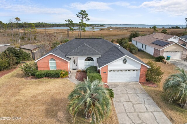 single story home with a garage, a front lawn, and a water view