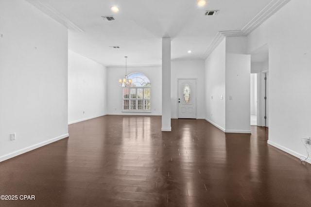 foyer entrance featuring crown molding, dark wood-type flooring, and an inviting chandelier