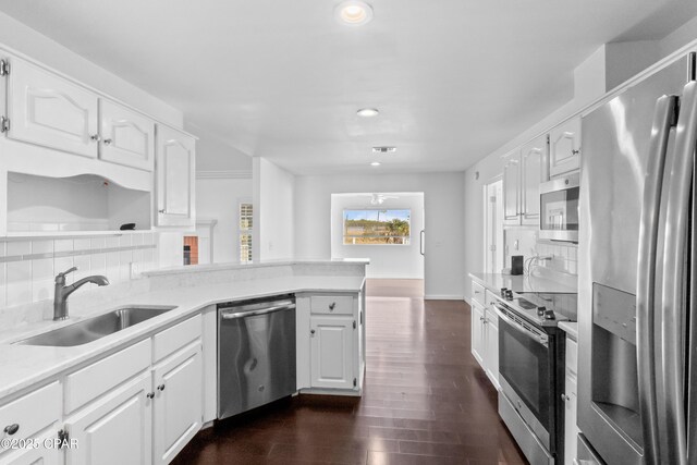 kitchen featuring a fireplace, kitchen peninsula, sink, and white cabinets