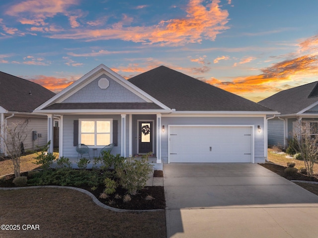 view of front of house featuring covered porch, driveway, a shingled roof, and an attached garage