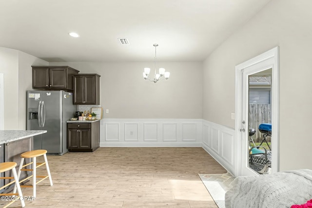 kitchen featuring visible vents, light stone counters, light wood-style floors, a chandelier, and stainless steel refrigerator with ice dispenser