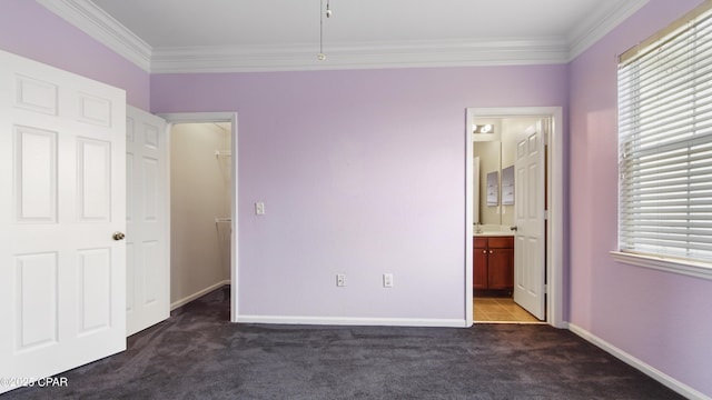 unfurnished bedroom featuring crown molding, ensuite bath, multiple windows, and dark colored carpet