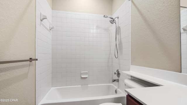 full bathroom with tiled shower / bath, vanity, and toilet