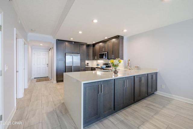 kitchen featuring stainless steel appliances, ornamental molding, dark brown cabinets, and kitchen peninsula