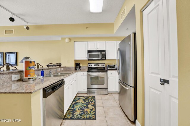 kitchen featuring visible vents, appliances with stainless steel finishes, white cabinetry, a sink, and light tile patterned floors