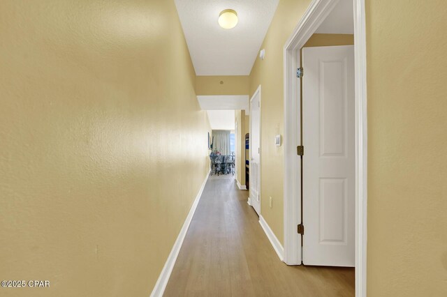 hall with baseboards and wood finished floors