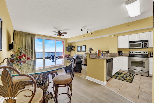 kitchen featuring white cabinets, visible vents, a peninsula, ceiling fan, and appliances with stainless steel finishes