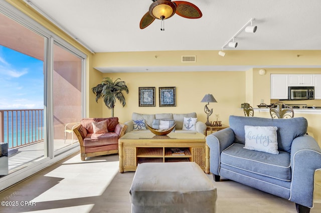 living room featuring visible vents, track lighting, light wood-style floors, and ceiling fan