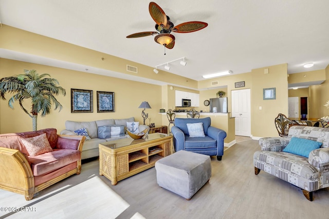 living area with wood finished floors, baseboards, ceiling fan, and visible vents