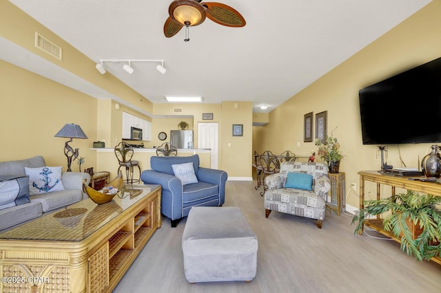 living area with baseboards, visible vents, wood finished floors, and ceiling fan