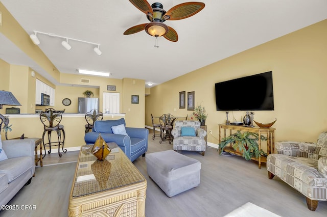 living room with visible vents, track lighting, baseboards, ceiling fan, and wood finished floors