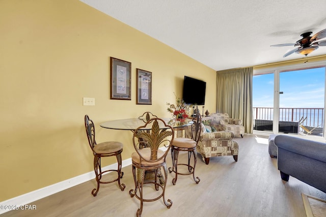 living room with baseboards, wood finished floors, ceiling fan, and a textured ceiling