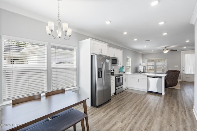 kitchen with white cabinetry, appliances with stainless steel finishes, a peninsula, and light wood finished floors