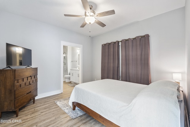 bedroom with a ceiling fan, ensuite bathroom, baseboards, and wood finished floors