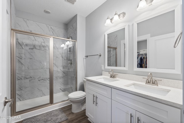 full bathroom featuring toilet, a marble finish shower, and a sink