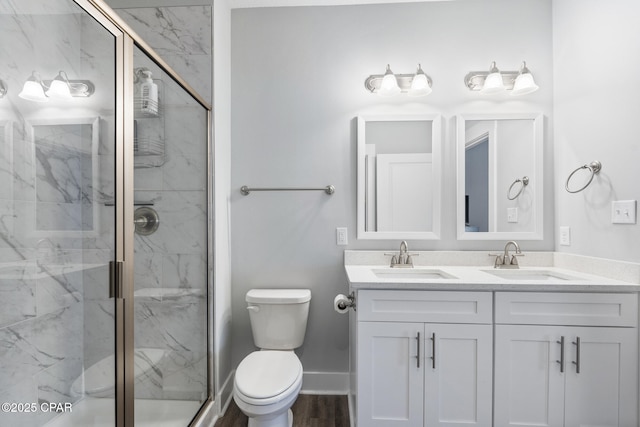 bathroom featuring a sink, a marble finish shower, and toilet