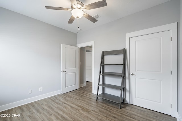 unfurnished bedroom with visible vents, baseboards, wood finished floors, and a ceiling fan