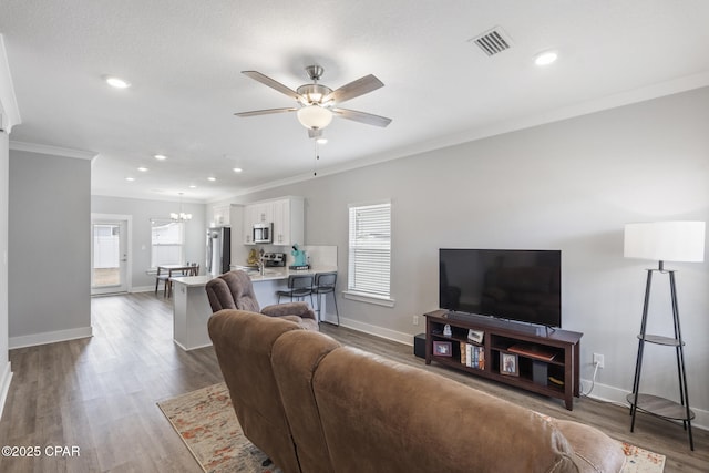 living area with dark wood-type flooring, crown molding, visible vents, and baseboards