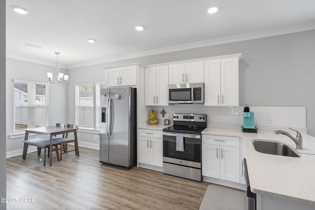 kitchen with light wood-type flooring, ornamental molding, a sink, tasteful backsplash, and stainless steel appliances